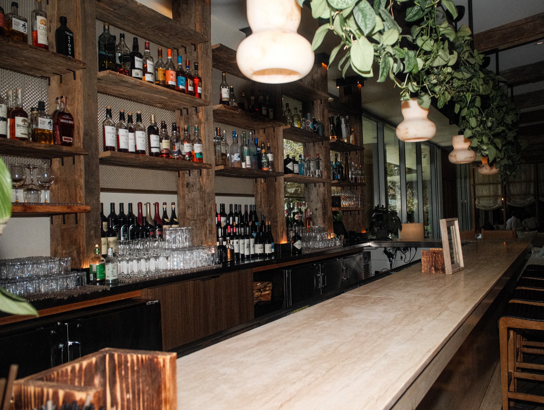Marble-topped bar lined with spirits and hanging greenery at 1 Hotel West Hollywood
