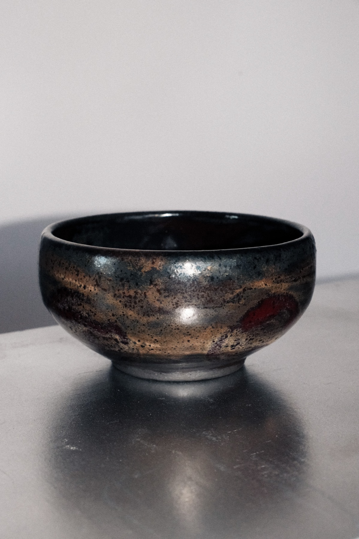 Dark speckled serving bowl with a red glaze accent