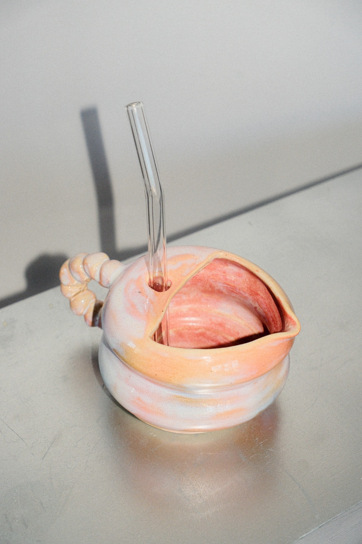 Blush pink pouring bowl with a twisted handle and glass straw
