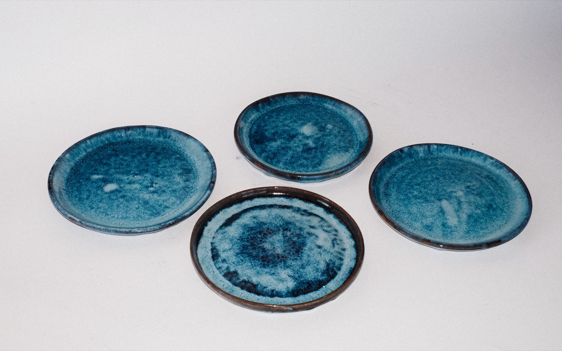Set of four side plates in a mottled ocean-blue glaze